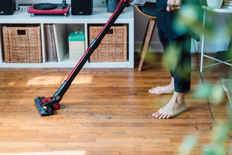 A person cleaning a wooden desk with a spray bottle and cloth, showcasing tidiness.